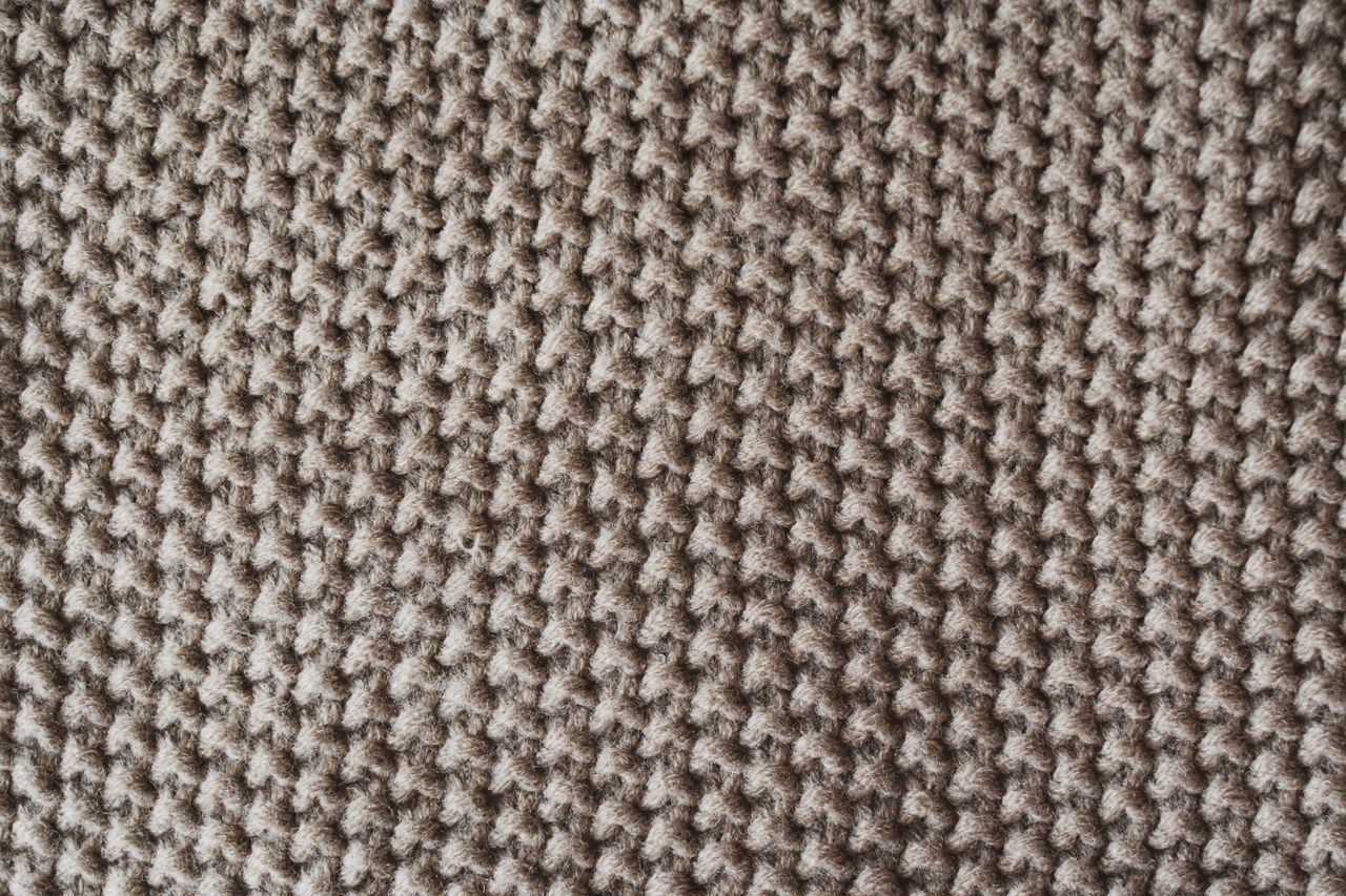 Detailed close-up of a textured knitted wool fabric, ideal for textile and pattern designs.