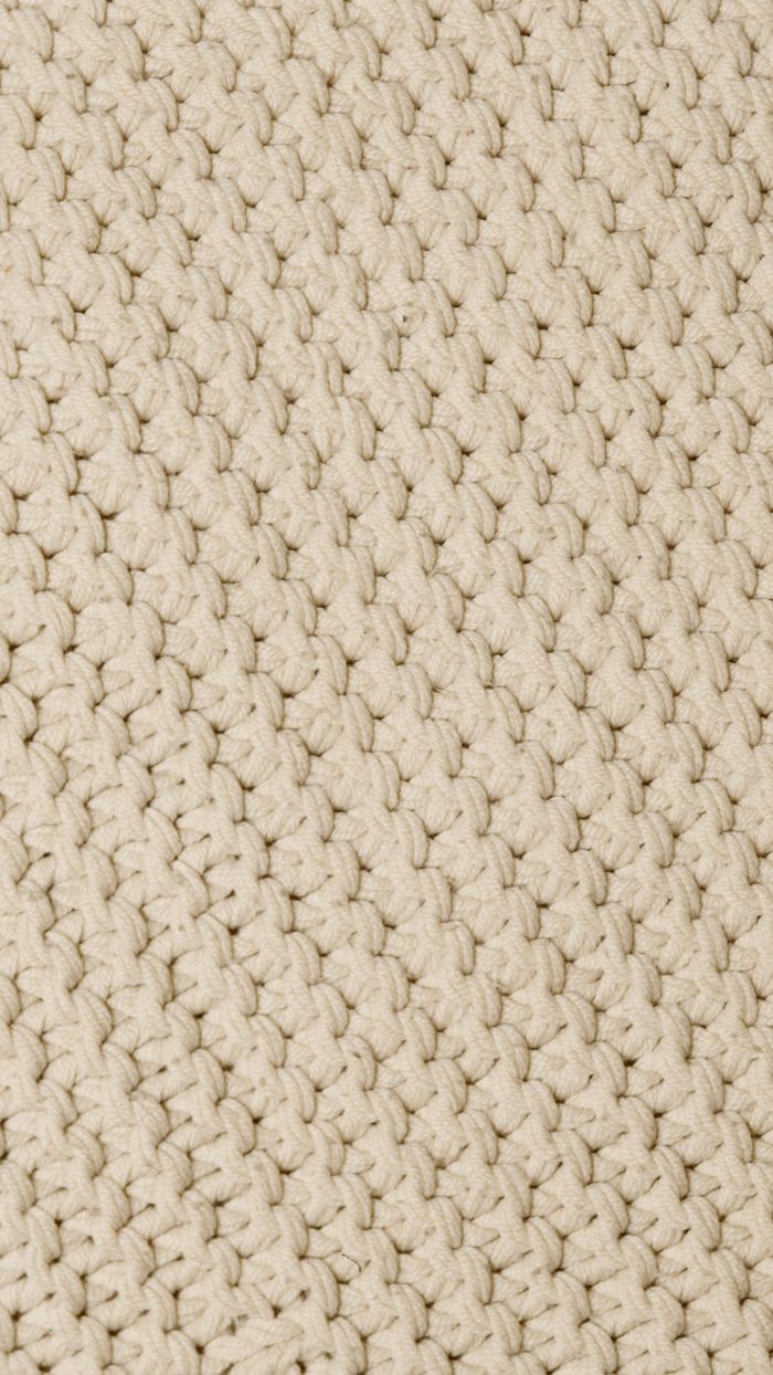 Detailed close-up of beige knit fabric showcasing intricate woven texture.